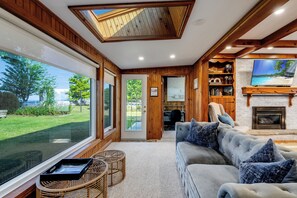 A spacious living room with a large window, a fireplace, and a comfortable seating area. - Sunsets by the Bay - Your Waterfront Oasis (Leamington)