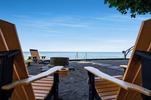 A beachside seating area with wooden chairs and a table, overlooking the sea. - Sunsets by the Bay - Your Waterfront Oasis (Leamington)