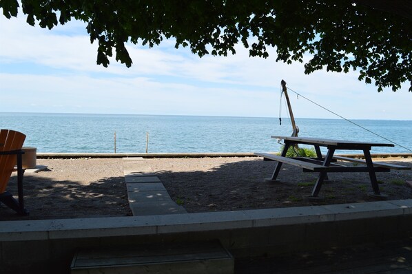 Et picnicbord og en stol ved vandet med udsigt over havet.