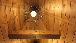 Un plafond en bois orné de luminaires suspendus aux formes géométriques et une fenêtre en bas.