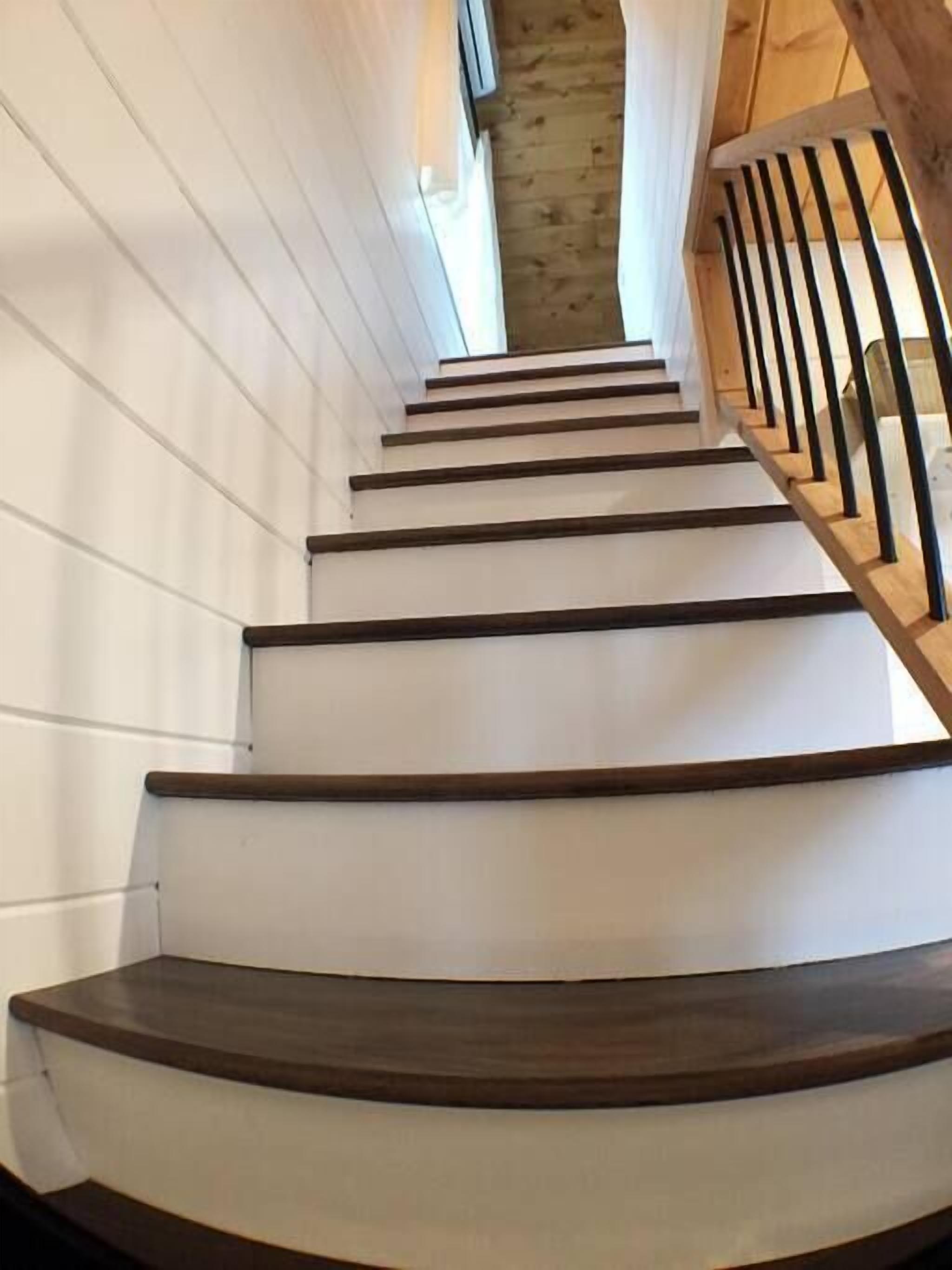 Eine Holztreppe mit weißen Wänden und einem Holengeländer.