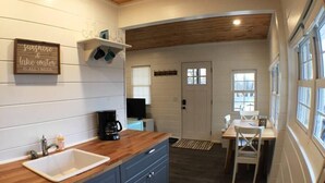 Une cuisine avec un plan de travail en bois, un évier et des placards. On peut voir une machine à café sur le plan de travail.