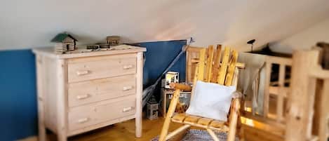 Cozy loft-style room with a sloped ceiling, wooden floor, and a small dresser.