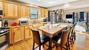 A modern kitchen with wooden cabinets, a granite countertop, and a central island with bar stools.