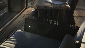 A sunlit outdoor seating area with a wicker chair and a cushioned bench, overlooking a body of water and trees. -  Beautiful Home with private Infinity Edge Pool 2 miles to ZNP main entrance (Springdale)