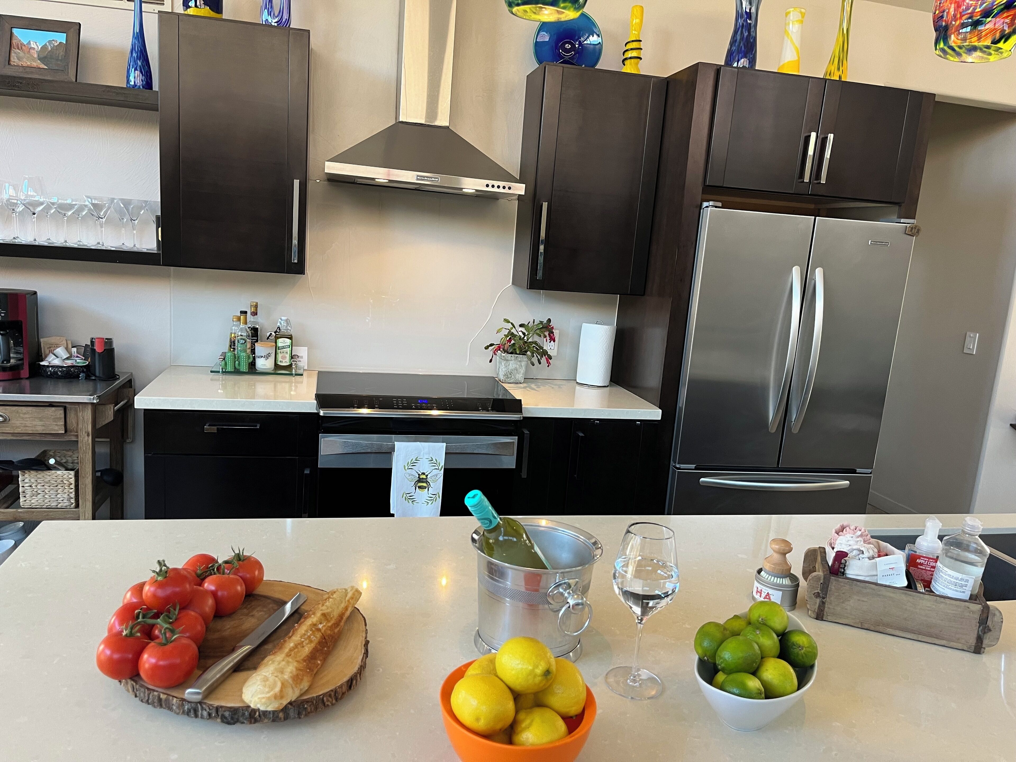 A modern kitchen with dark cabinets, stainless steel appliances, and a marble countertop.
