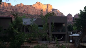 A modern building with a flat roof and large windows, surrounded by greenery and mountains in the background. -  Beautiful Home with private Infinity Edge Pool 2 miles to ZNP main entrance (Springdale)