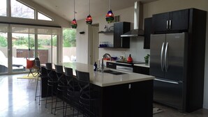 A modern kitchen with a central island, black cabinets, stainless steel appliances, and hanging pendant lights. -  Beautiful Home with private Infinity Edge Pool 2 miles to ZNP main entrance (Springdale)