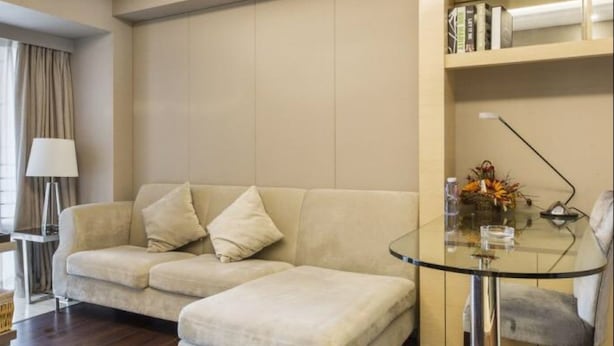 A modern living room with a sofa, ottoman, and a glass coffee table. - Tata Hotel Apartment Shenzhen (Shenzhen)