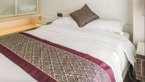 A hotel room with a large bed, a bedside table, a nightstand, and a window with blinds. - Tata Hotel Apartment Shenzhen (Shenzhen)