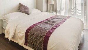 A hotel room with a large bed, a nightstand, a lamp, and a window with curtains. - Tata Hotel Apartment Shenzhen (Shenzhen)