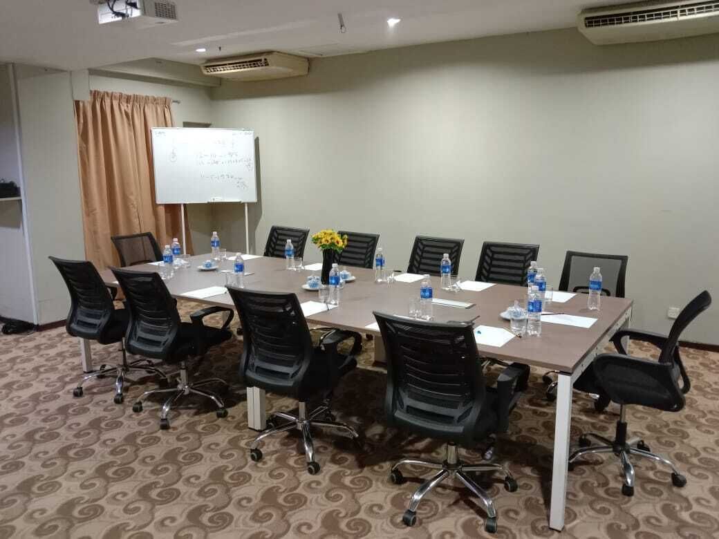 A conference room with a long table, black chairs, water bottles, and a whiteboard.