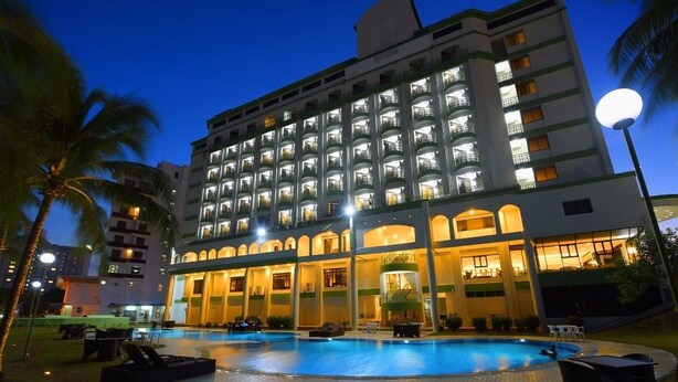 A multi-story hotel with a swimming pool, palm trees, and outdoor seating areas. - De Greenish Village Langkawi (Langkawi)