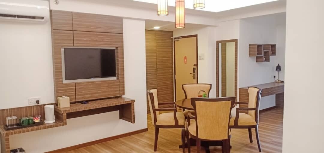 A modern living room with a flat-screen TV, wooden furniture, and a dining area with chairs and a table.