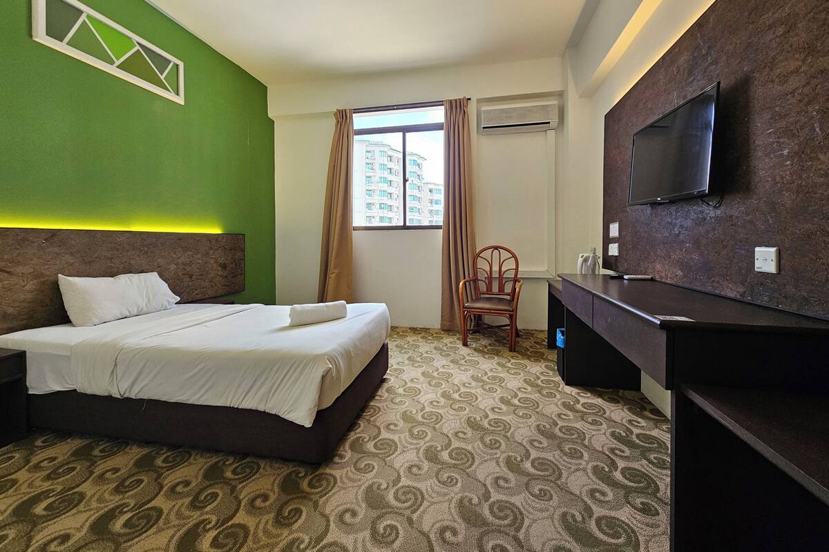 Une chambre d’hôtel équipée d’un lit, d’une chaise, d’un bureau, d’une télévision et d’un appareil de climatisation.