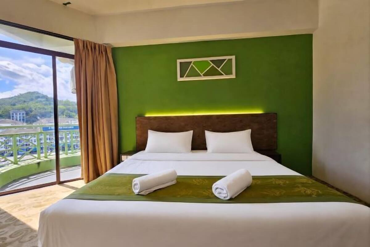 Une chambre d’hôtel avec un lit, une vue sur un balcon et un mur végétal.