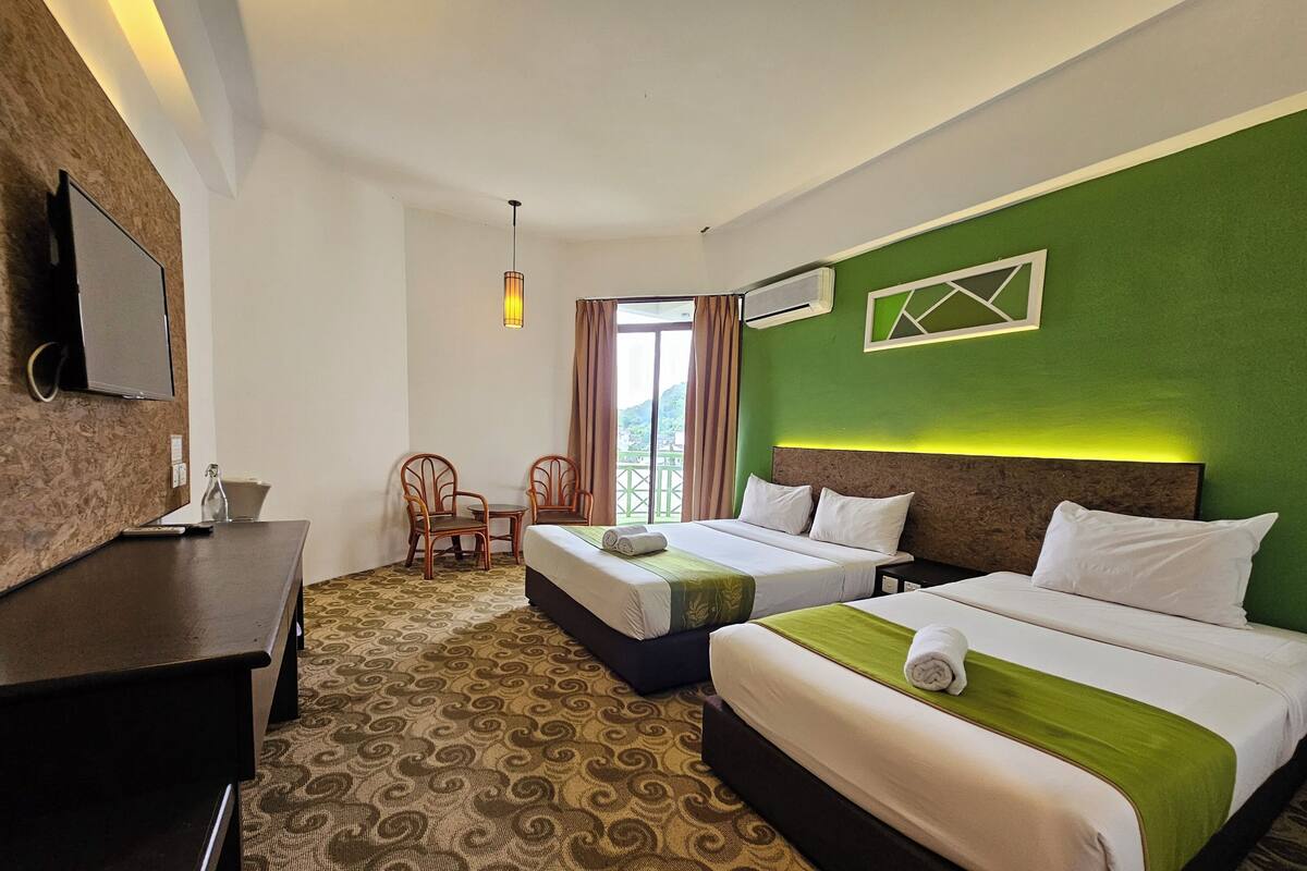 Une chambre d’hôtel avec deux lits, un bureau, une chaise, une télévision et une fenêtre avec des rideaux.