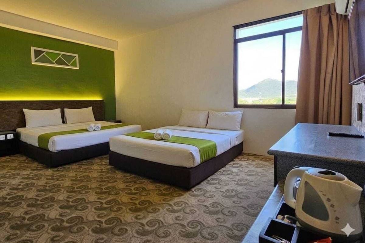 Une chambre d’hôtel avec deux lits, un bureau, une bouilloire et une fenêtre donnant sur un beau paysage.