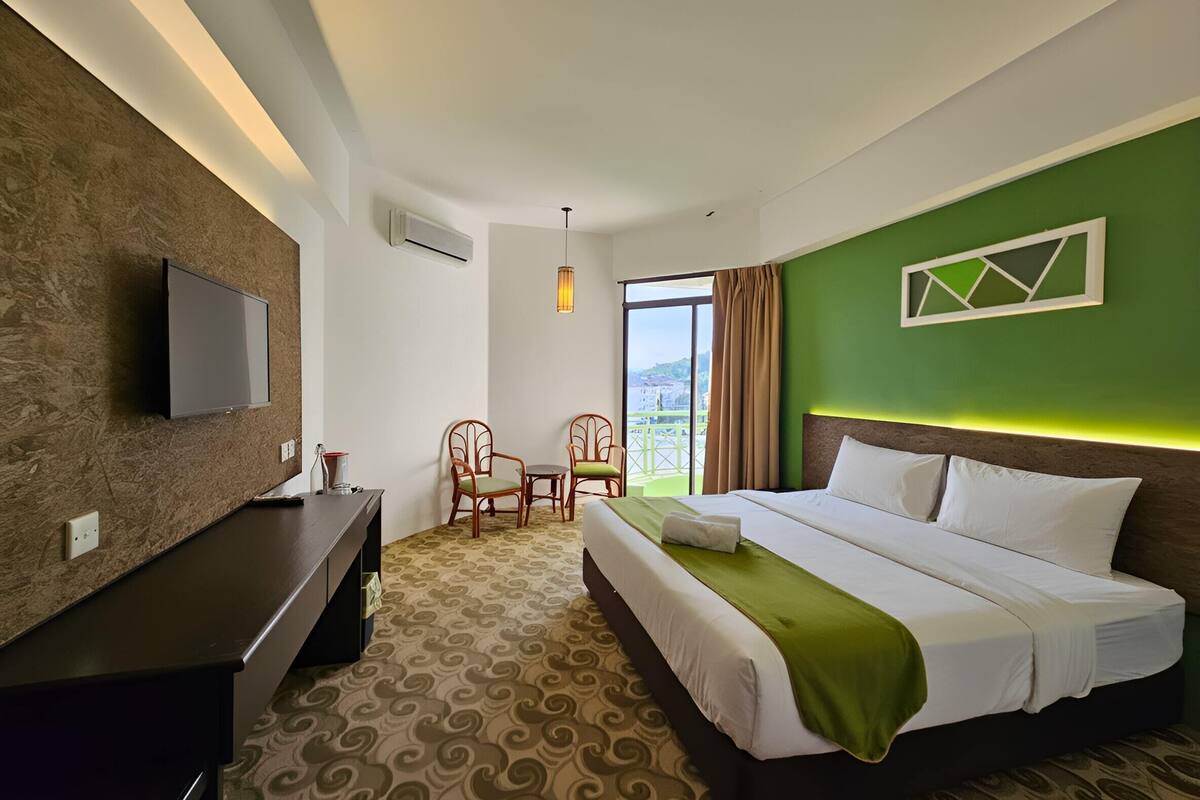 Une chambre d’hôtel équipée d’un lit, d’un bureau, d’une chaise, d’une télévision et offrant une vue sur l’extérieur.