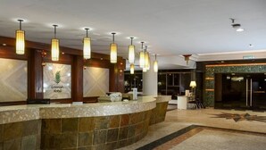 A hotel reception area with a curved reception desk, multiple pendant lights, and a marble floor. - De Greenish Village Langkawi (Langkawi)