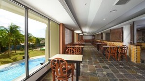 A restaurant with a view of a swimming pool and palm trees. - De Greenish Village Langkawi (Langkawi)