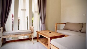 Una habitación con una cama de madera, una silla de madera, una mesita de madera y una ventana con cortinas.