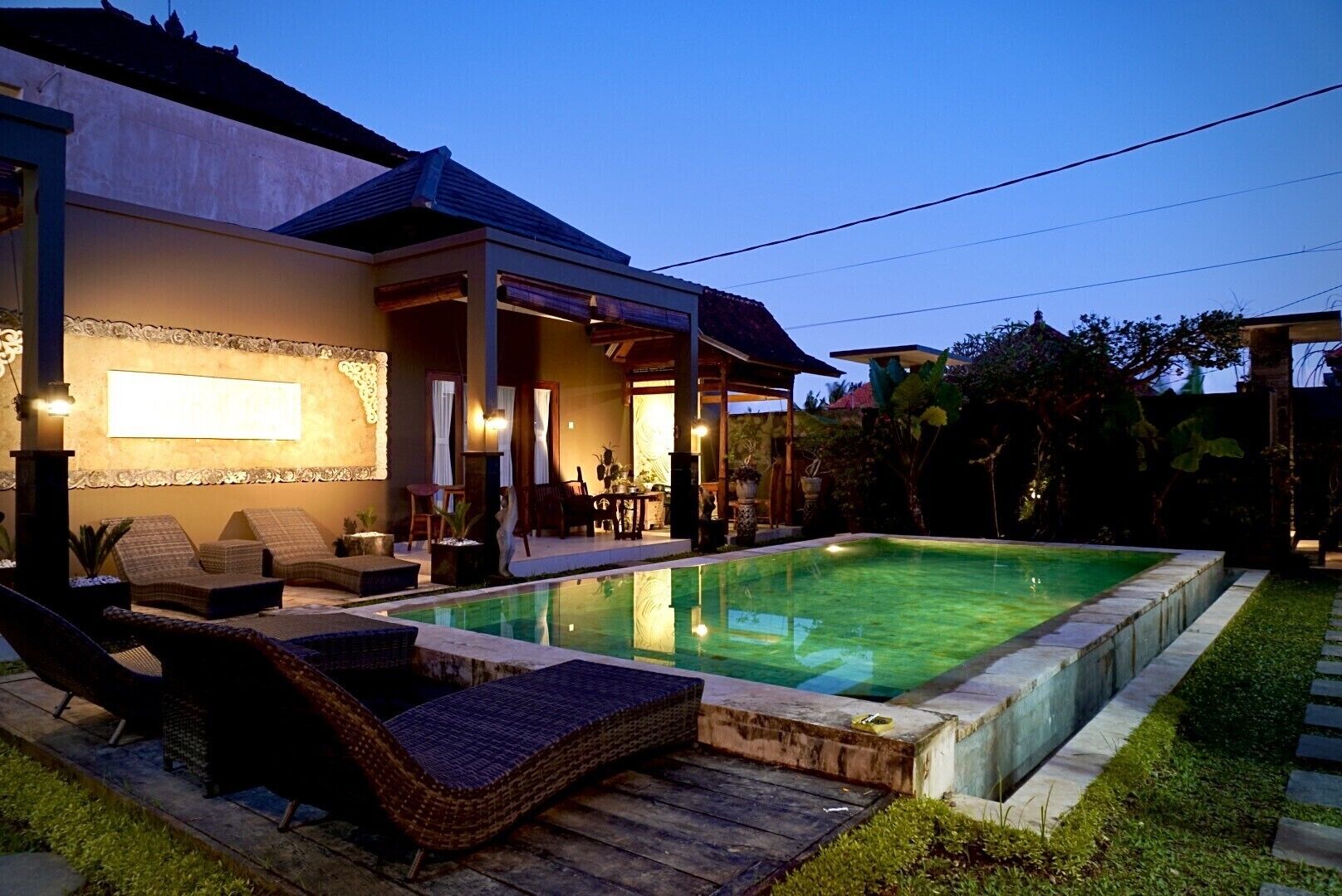 A modern house with a swimming pool, outdoor seating, and a covered patio area.