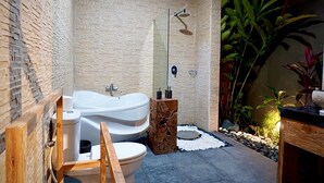 Un baño moderno con una bañera independiente, ducha y retrete.