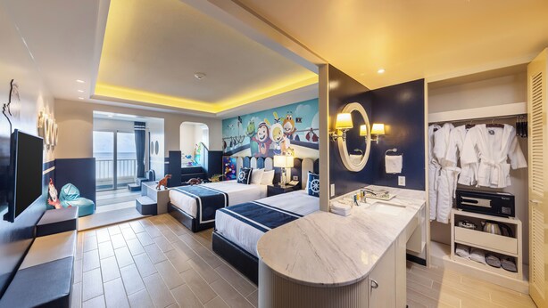A hotel room with two beds, a vanity with a mirror, a seating area, and a view of the balcony.