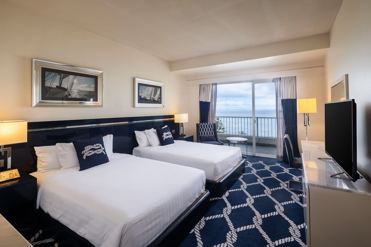 Een hotelkamer met twee bedden, een televisie, een bureau en een balkon met uitzicht.