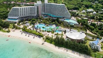 Luchtbeeld van een resort met verschillende hotelgebouwen, een strand en een groot zwembad.
