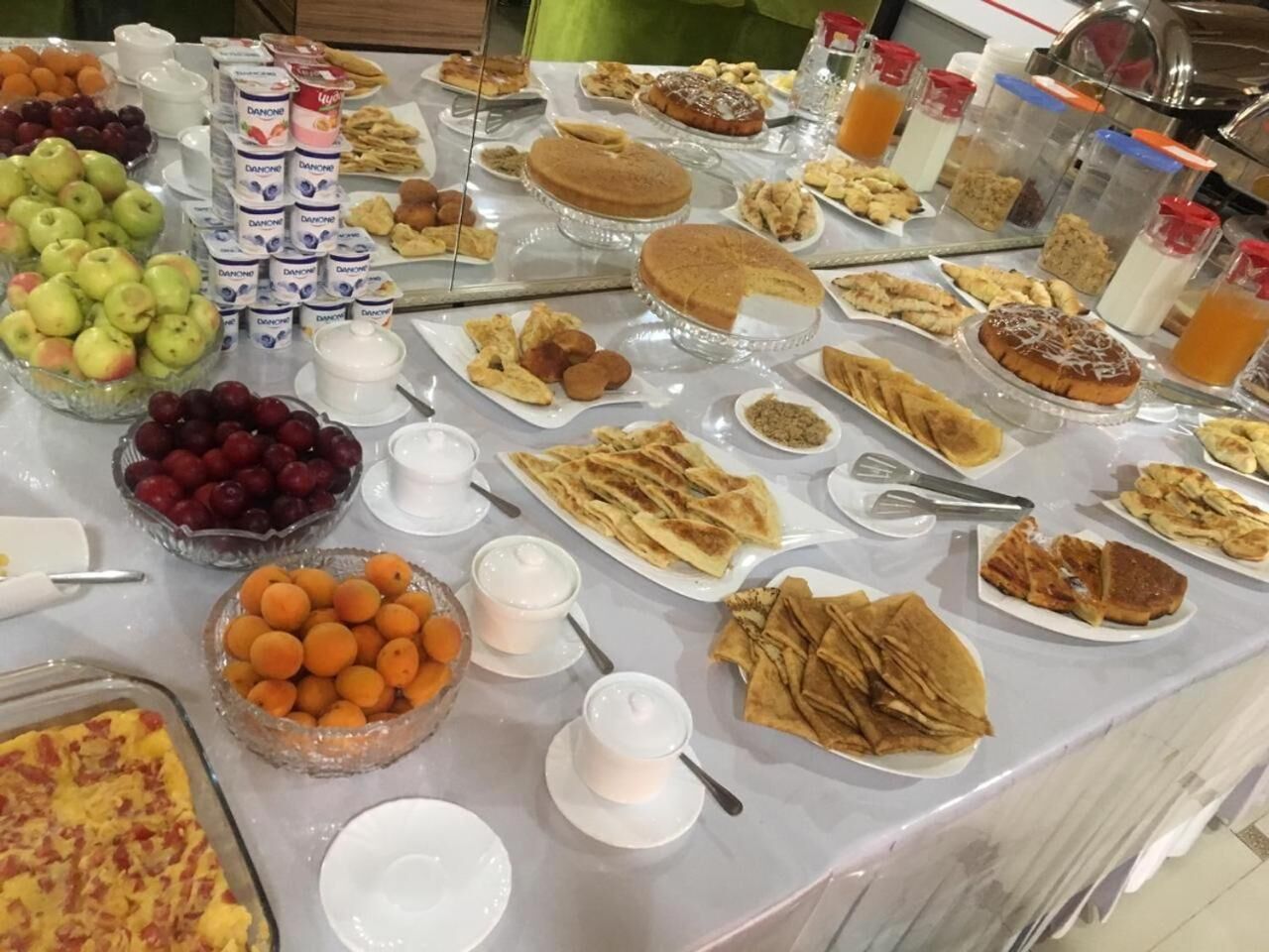 A buffet with various food items including fruits, pastries, and beverages.