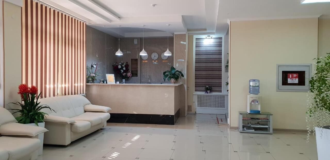 A modern reception area with a sofa, a reception desk, pendant lights, and a water dispenser.
