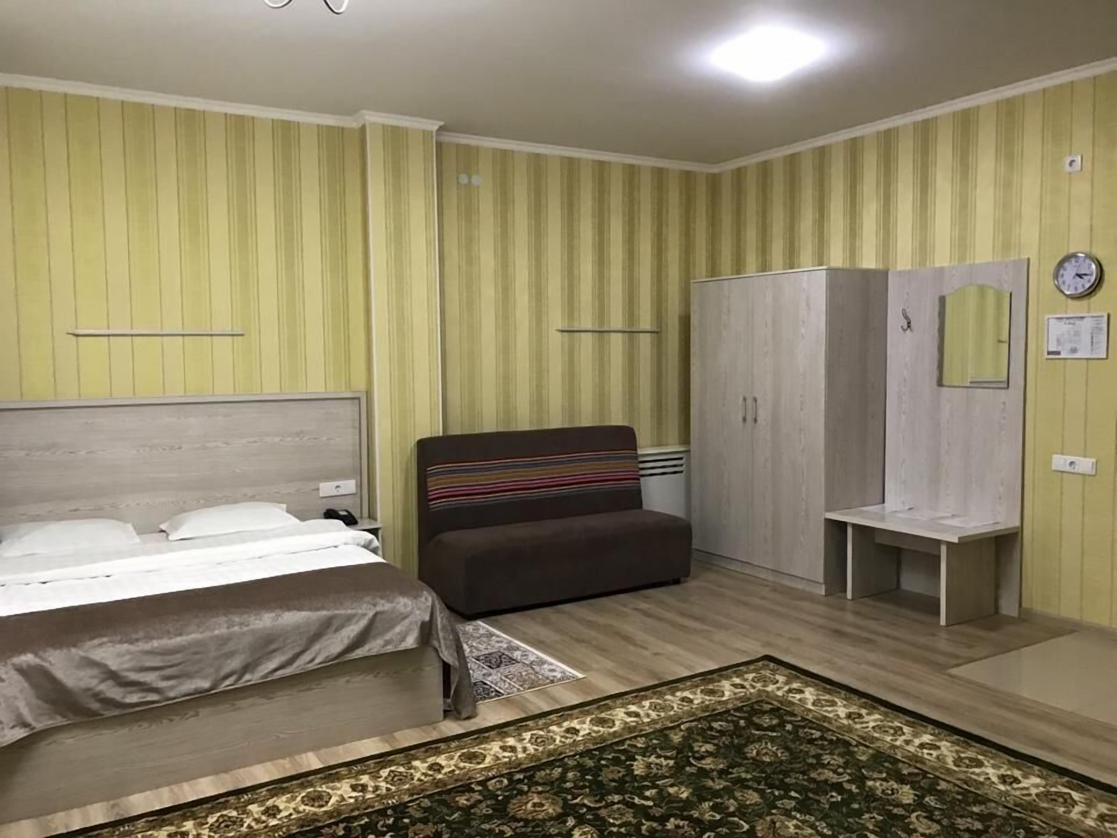 A bedroom with a bed, a sofa, a wardrobe, and a small table.