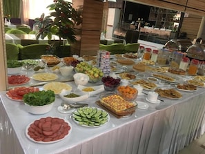 Un bufé con diversas opciones de comida, incluyendo ensaladas, frutas y postres.