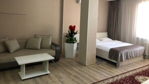 Een hotelkamer met een bank, een bed, een witte bijzettafel en een potplant.