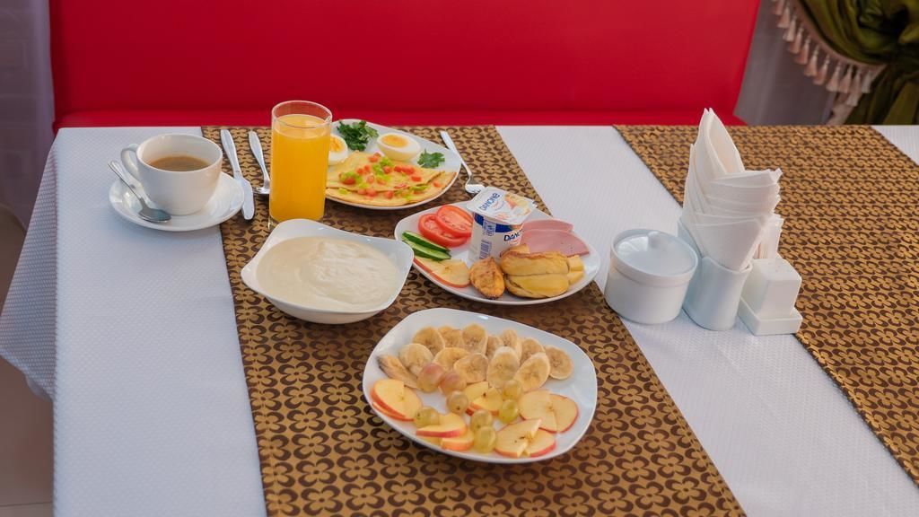 A breakfast table with a cup of coffee, orange juice, eggs, toast, fruit, and a bowl of soup.
