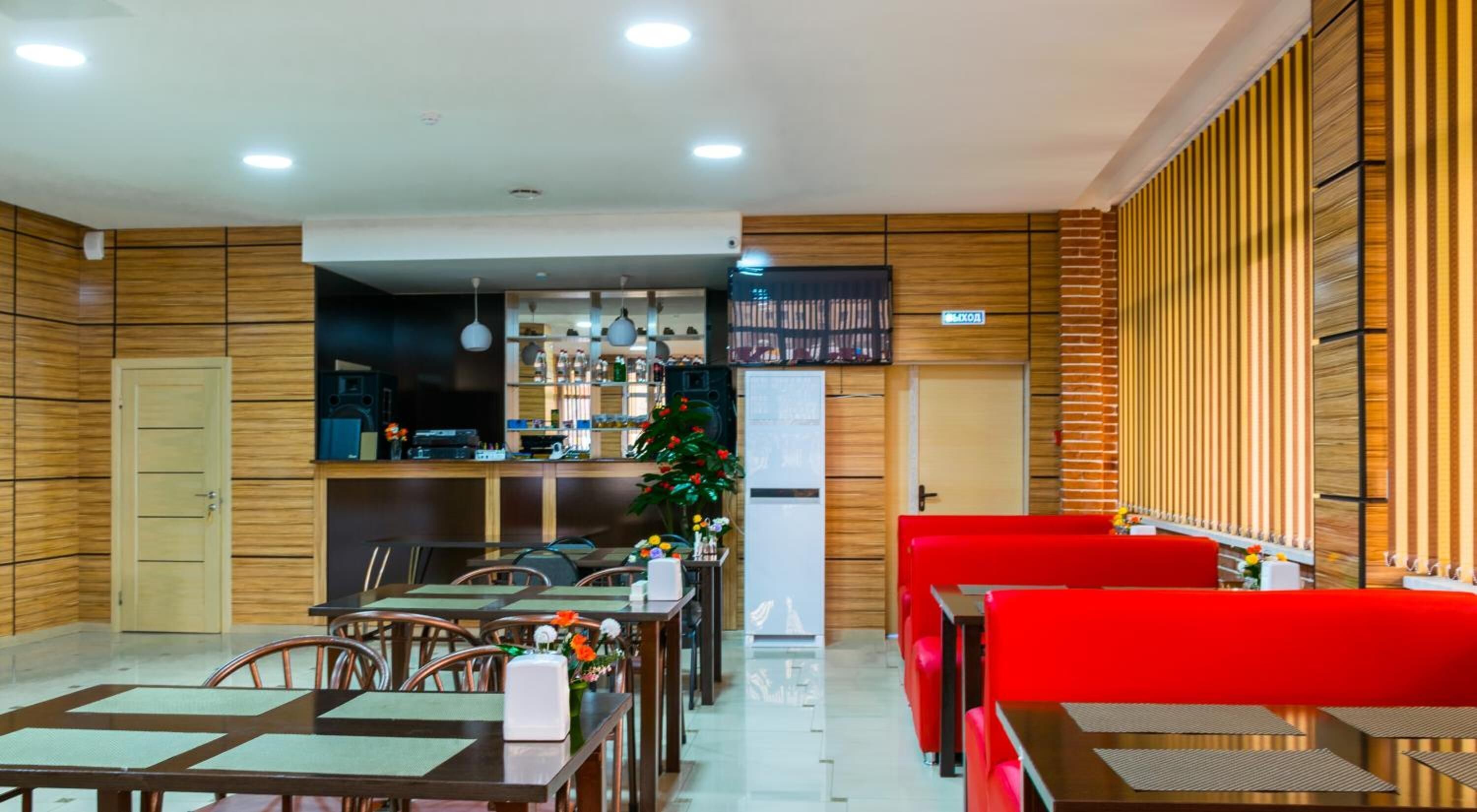 A restaurant with wooden panel walls, a bar area, and red seating.