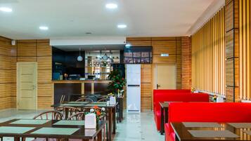 Un restaurante con paredes de paneles de madera, una zona de bar y asientos rojos.