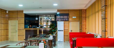 A restaurant with wooden panel walls, a bar area, and red seating.