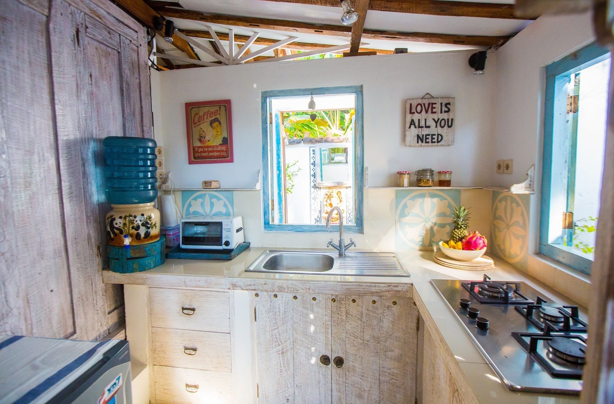Cocina compacta con lavamanos, estufa y ventana con vistas a zonas verdes.