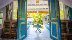 An open doorway leading to a courtyard with a table and chairs, surrounded by blue-painted walls and wooden cabinets.