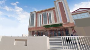 Un edificio moderno con amplios ventanales, techo plano y entrada protegida por una reja.