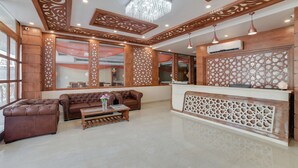 Un vestíbulo con mostrador de recepción, dos sofás, una mesa de centro y paneles de madera decorativos.