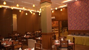 Un restaurante con mesas y sillas de madera, lámparas colgantes y una pared colorida.