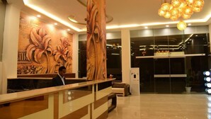 Un moderno vestíbulo de hotel con un mostrador de recepción, un gran mural floral y una lámpara de diseño único.