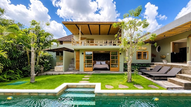 Una casa de dos pisos con piscina, balcón y jardín.