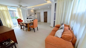 A modern living room with a sofa, dining area, and kitchen.