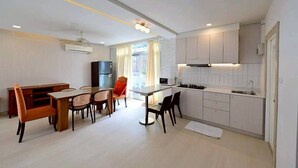 A compact kitchen with white cabinets, a dining area with a table and chairs, and a view of the outdoors through a window.
