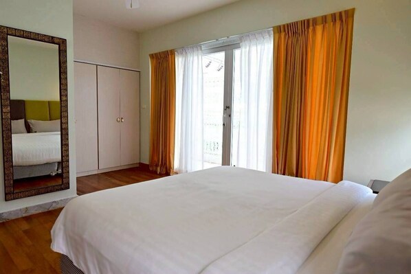 Un dormitorio con una cama grande, un armario y un ventanal corredero que da a un balcón.